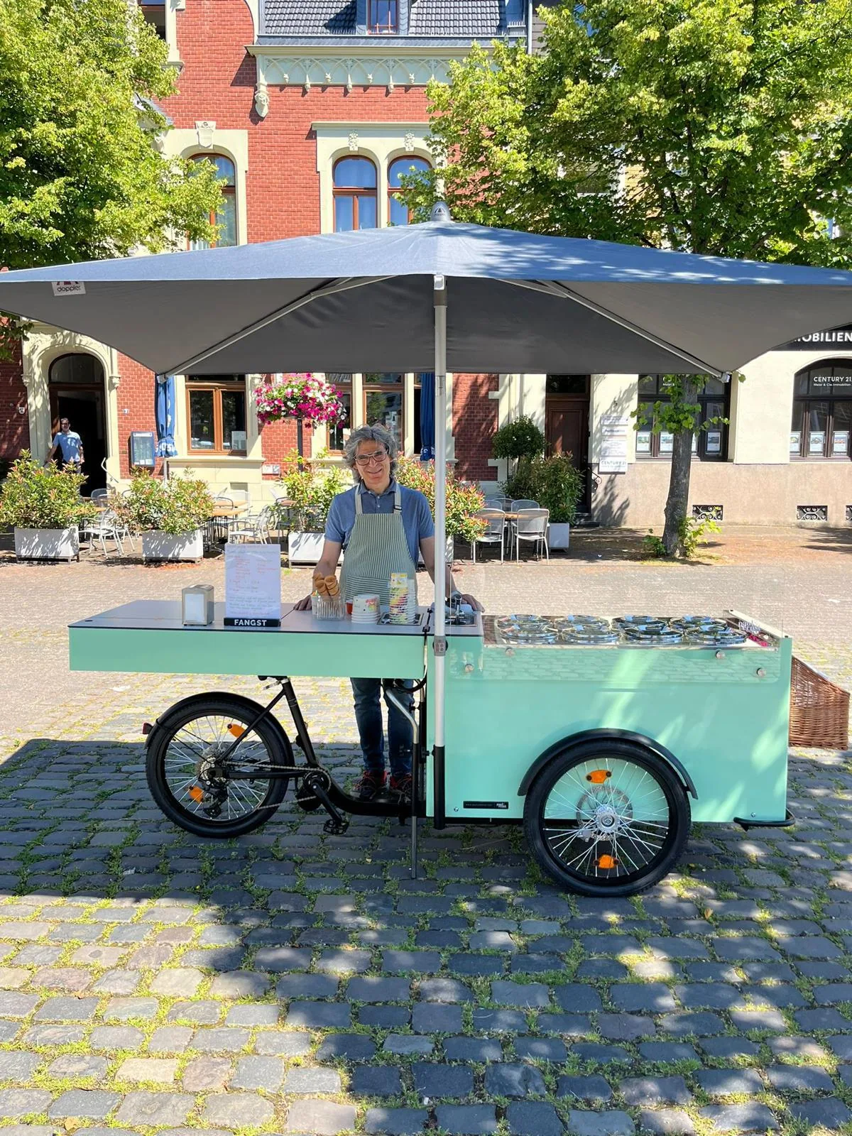 Mintgrünes Eisfahrrad mit Sonnenschirm, Eistruhe und Waffeltüten